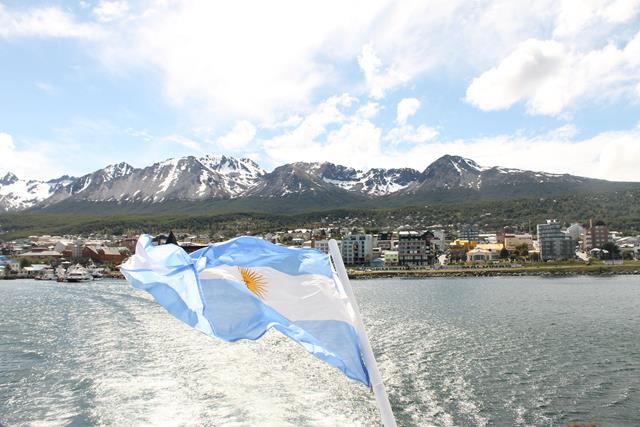 El horizonte con el puerto de la ciudad de Ushuaia y la bandera argentina hondeando al viendo